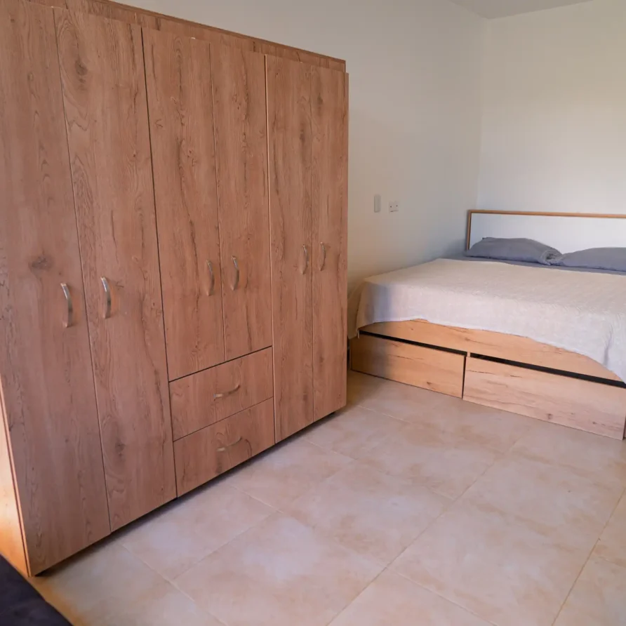 Dormitorio moderno en Casa Curva Bonita con armario de madera y cama doble con almacenaje integrado.