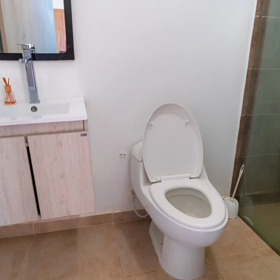 Baño moderno de cabaña en Calima El Darién con lavabo, espejo, inodoro y ducha de cristal.