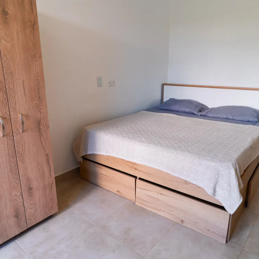 Dormitorio interior de cabaña en Calima el Darién con cama con almacenaje y amplio armario de madera clara.