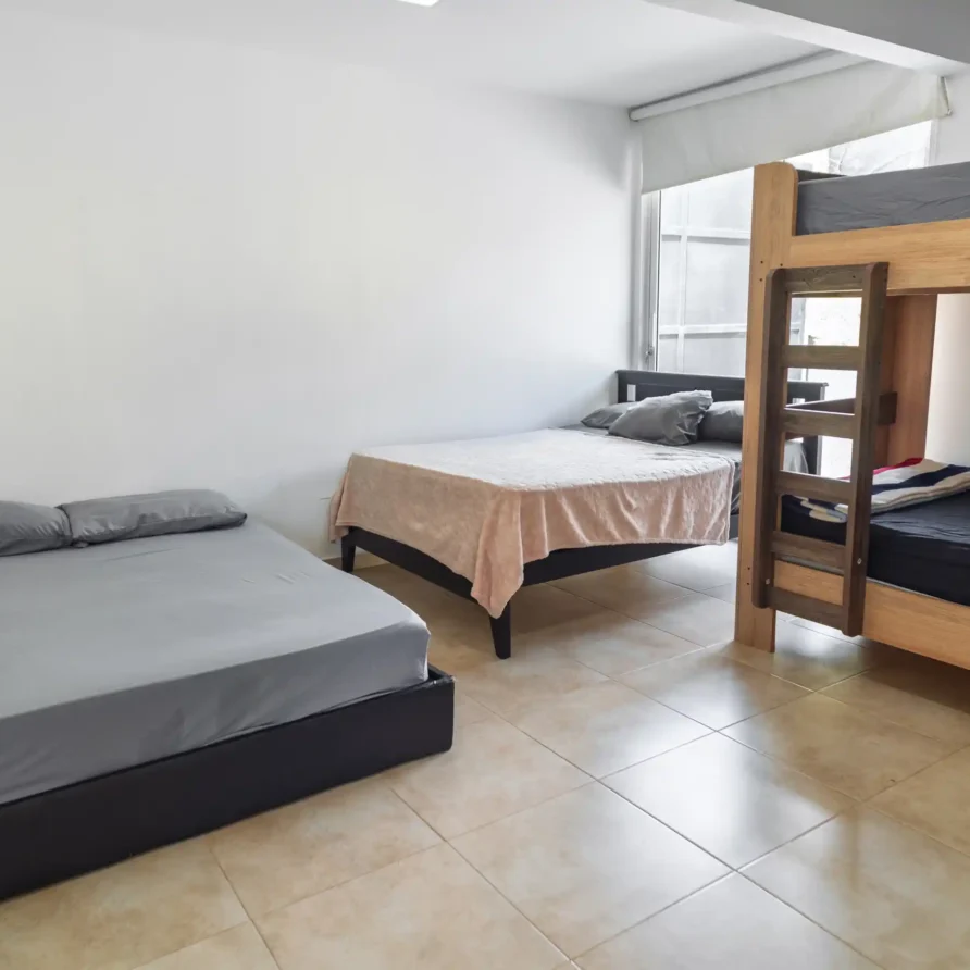 Habitación sencilla con tres camas individuales y una litera, ideal para grupos en Calima el Darién.