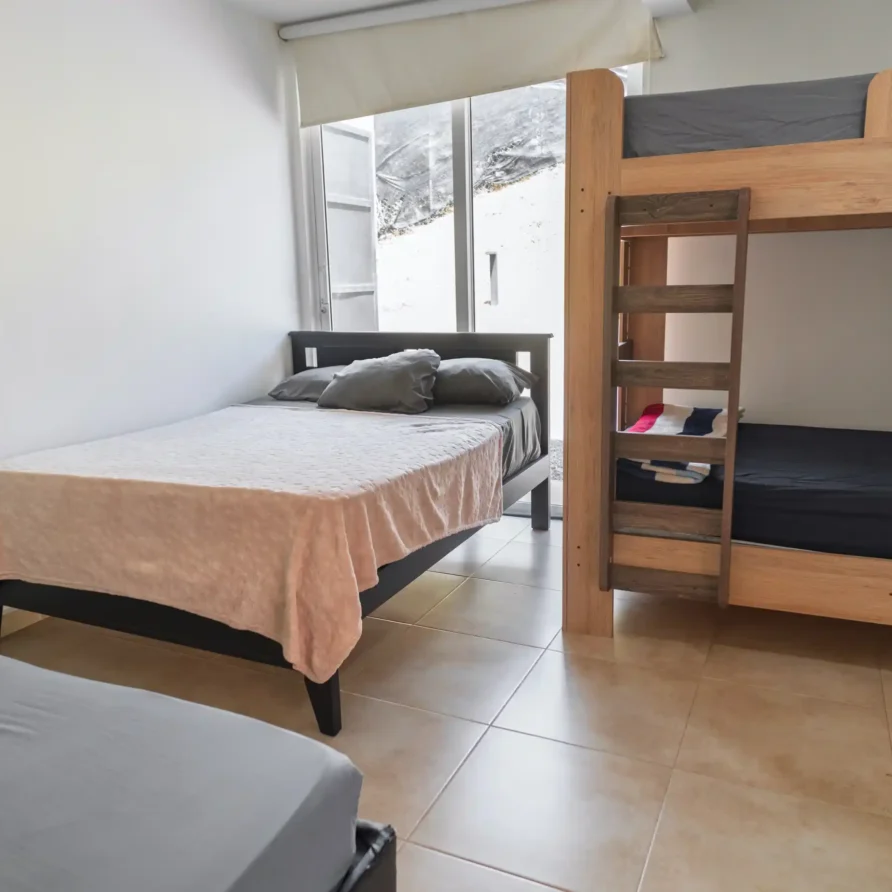 Habitación de cabaña sencilla con cama doble y literas, ideal para familias o grupos cerca de Lago Calima.