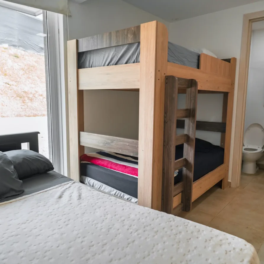 Habitación en Casa Curva Bonita con litera de madera y cama, junto a un baño privado.