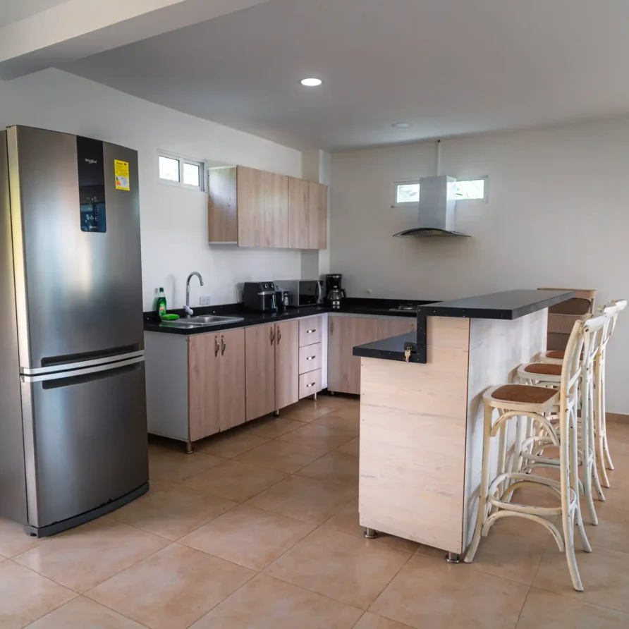 Cocina moderna y equipada con nevera de acero inoxidable y barra de desayuno en cabaña de Calima El Darién.