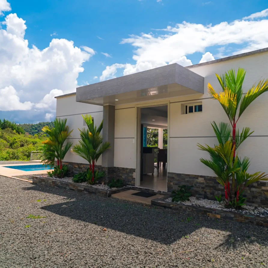 Moderna casa con piscina y jardín tropical en Calima el Darién, con vistas a la naturaleza y cielos azules.