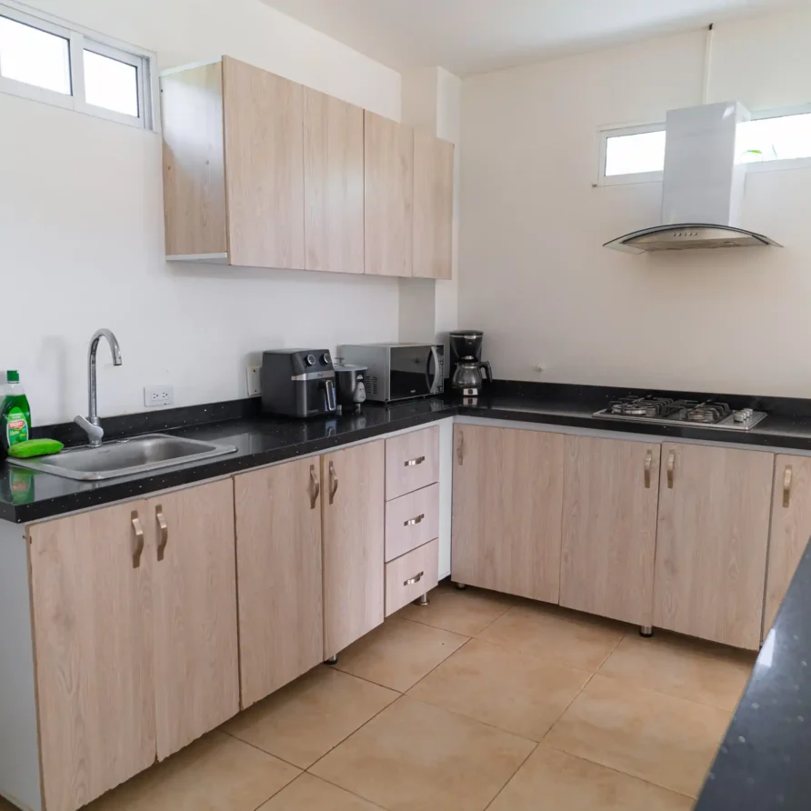 Cocina moderna de cabaña en Lago Calima con gabinetes de madera claros, encimeras oscuras y electrodomésticos.