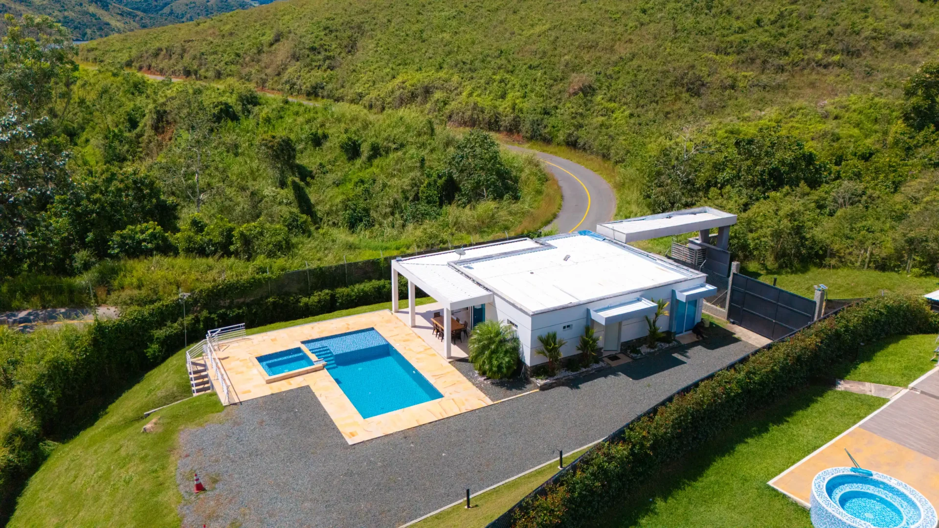 Casa moderna con piscina en un entorno de colinas verdes, cerca de Calima el Darién, con carretera sinuosa.