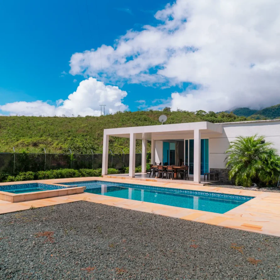 Cabaña moderna con piscina y jacuzzi en Calima El Darién, Colombia, rodeada de montañas verdes y cielo azul.