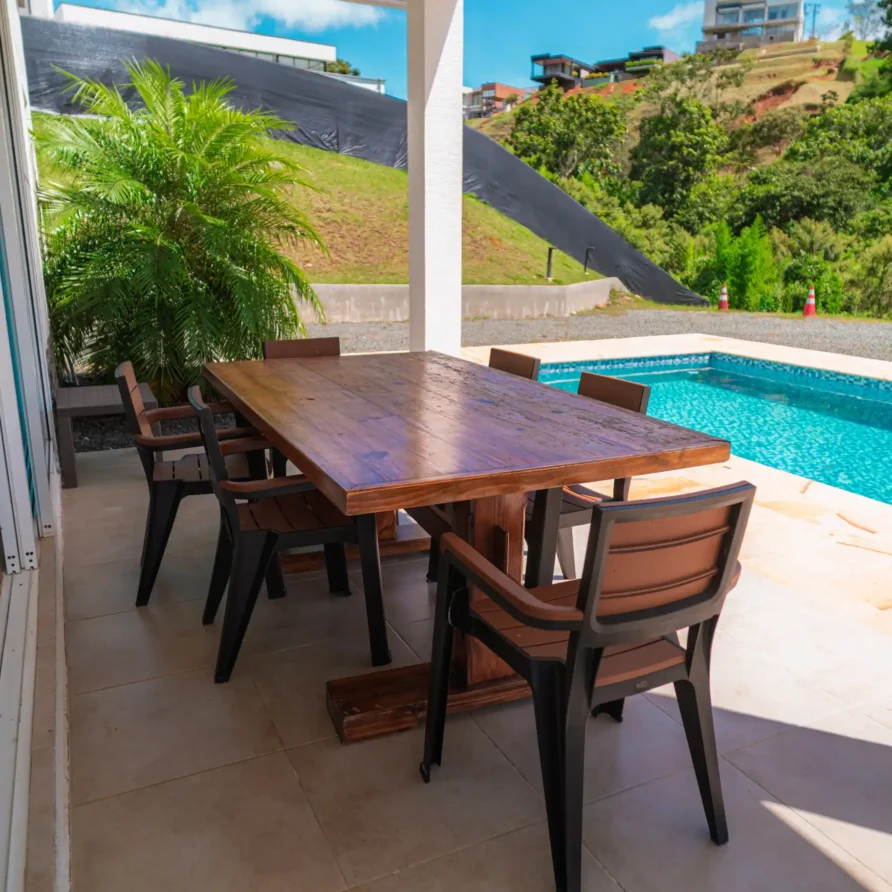 Patio exterior moderno con mesa de madera y sillas junto a piscina, en un entorno tropical de Calima el Darién.