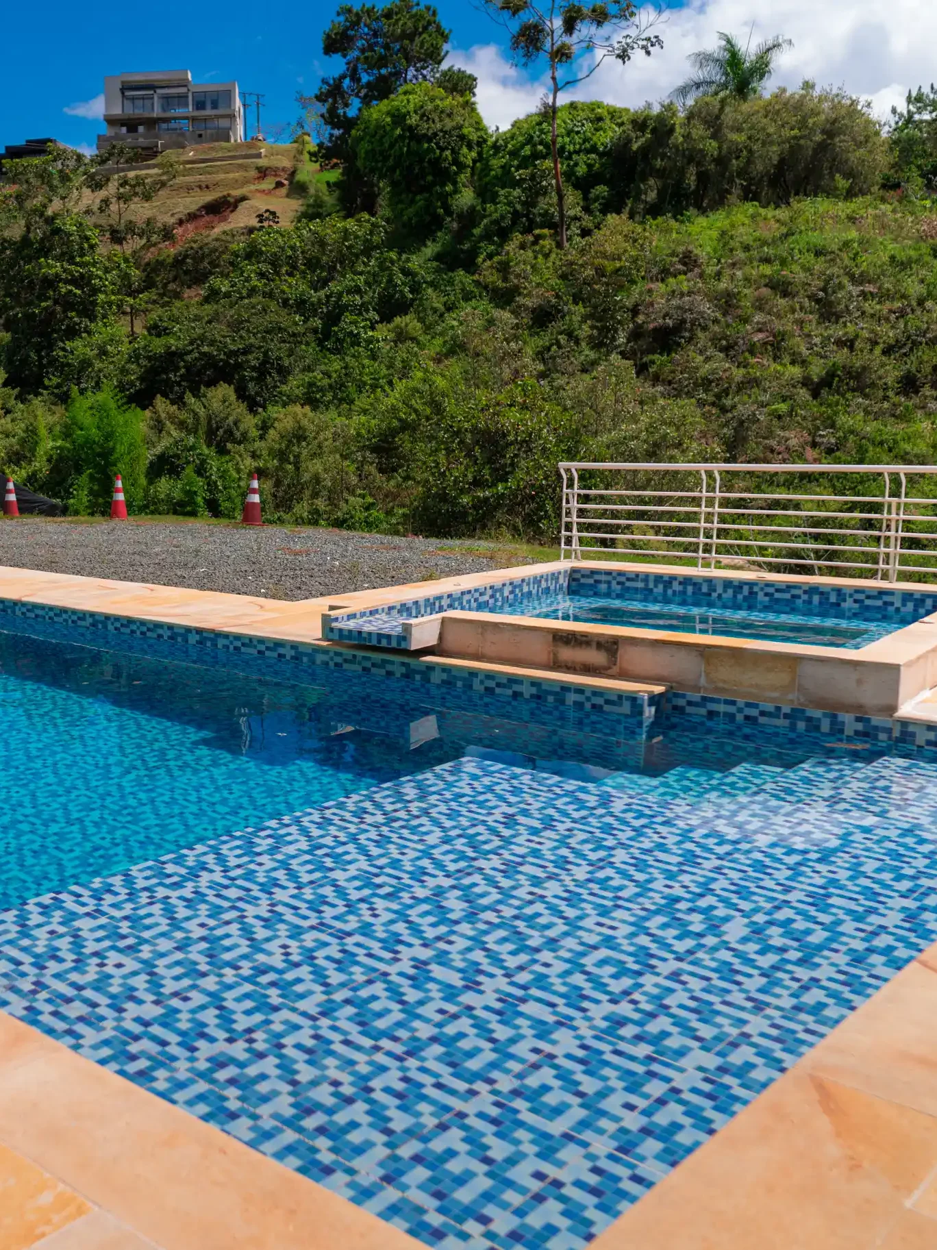 Área de piscina y spa con mosaicos azules, en una propiedad con vista a la naturaleza en Calima El Darién.